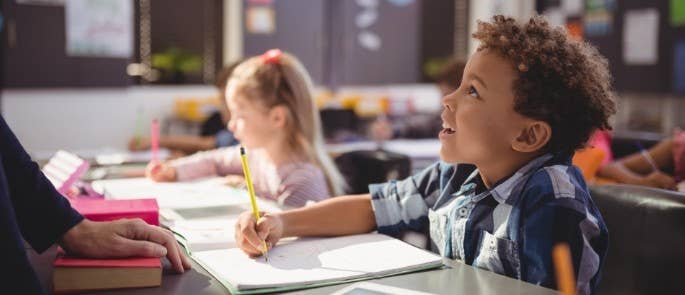 A child in a classroom listening to the teacher