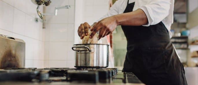 A man pouring food into a cooking pot