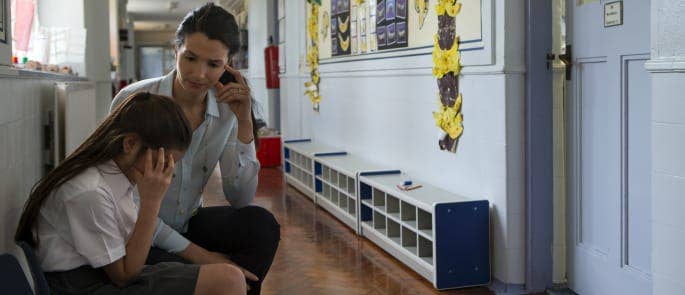 A teacher speaking to a student in a school hall