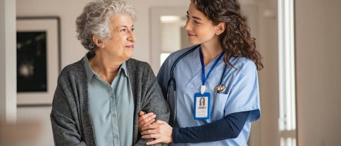 health and safety in care homes demonstrated by a care worker walking arm in arm with an elderly woman