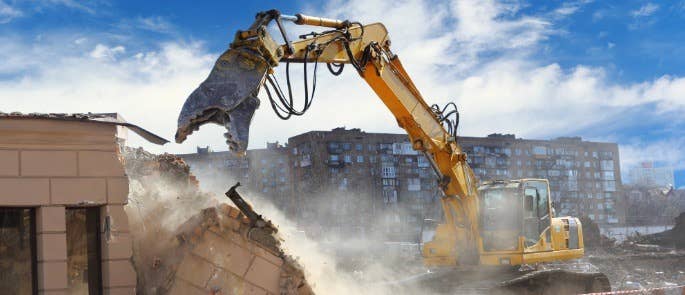 Building being demolished by construction vehicle