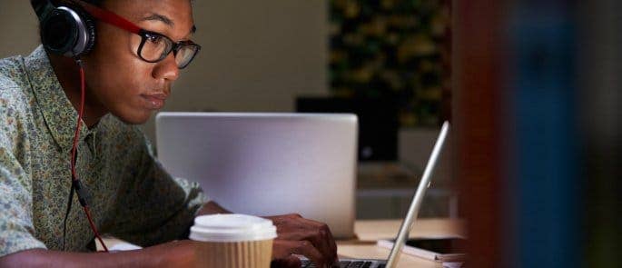 person using computer and drinking coffee late at night