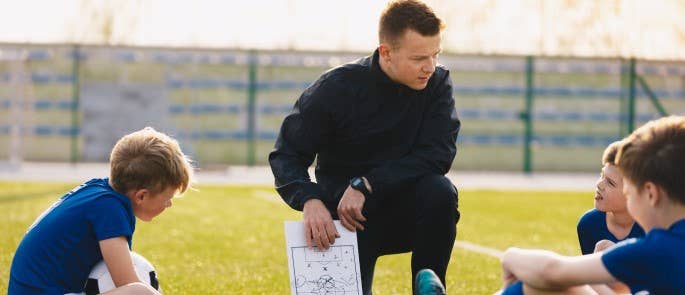 a man coaching children to play football