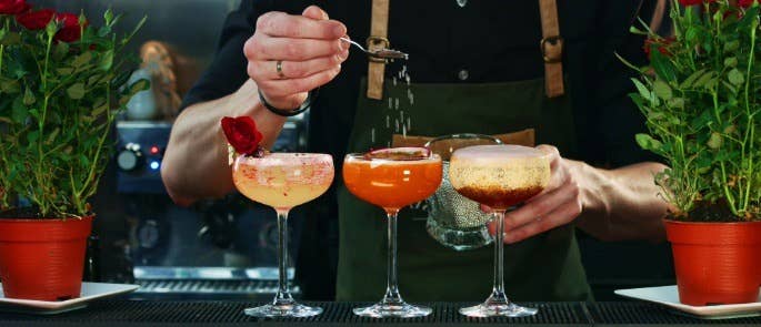 Three colourful cocktails sitting on a bar top ready to go to customers.