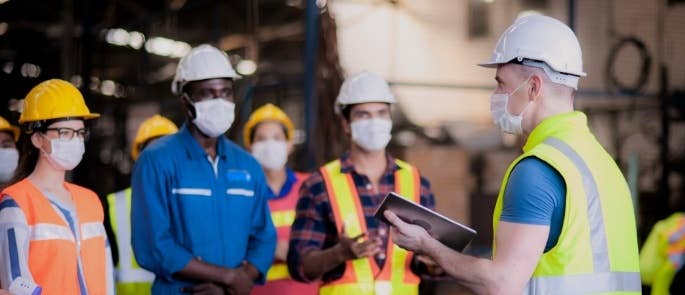 Construction workers having a stand up toolbox talk on site