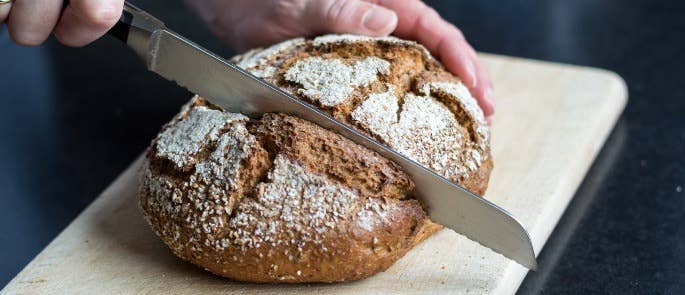 Baker cutting bread on a wooden chopping board