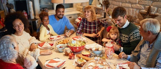 Large family of sitting round table after Christmas dinner talking and smiling