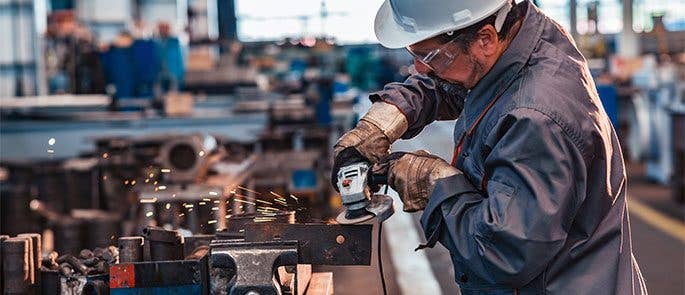 A worker using a hand-held grinding machine 