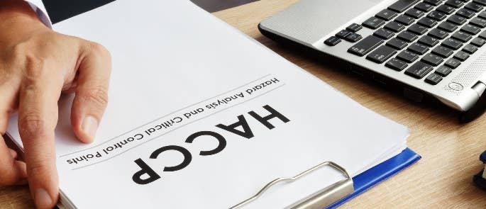 Close up of the HACCP paperwork alongside a laptop on a desk.