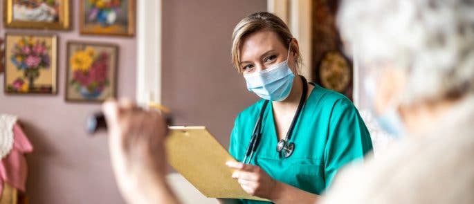 Nurse visiting a patient in her home, wearing a face covering for PPE