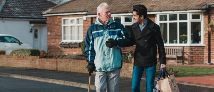 Volunteer assisting a gentleman across the road with his shopping