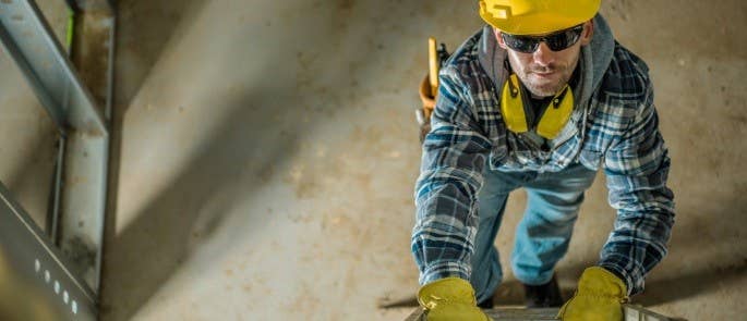 A man wearing PPE safely climbing up a ladder