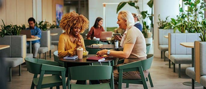 Two colleagues meeting in the office meal space 