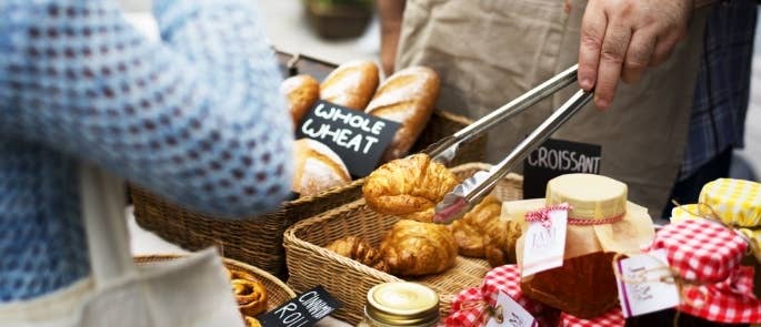 A man selling croissants and jam on a market stall