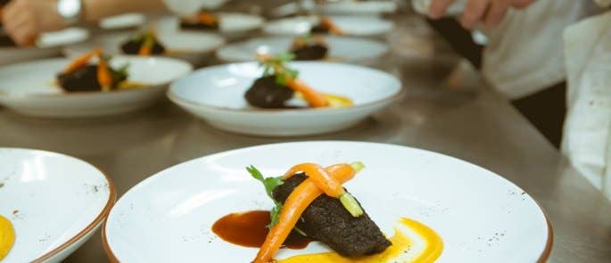 long line of plates with fancy food being plated up