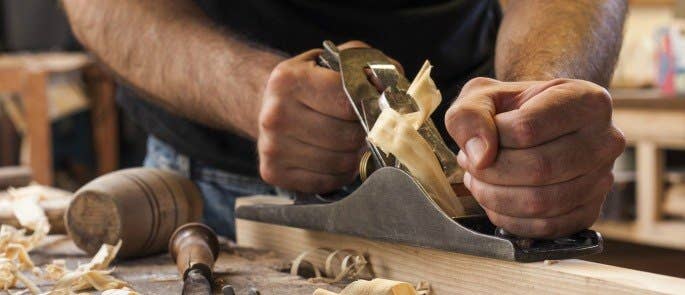 Carpenter sanding wood in a workshop