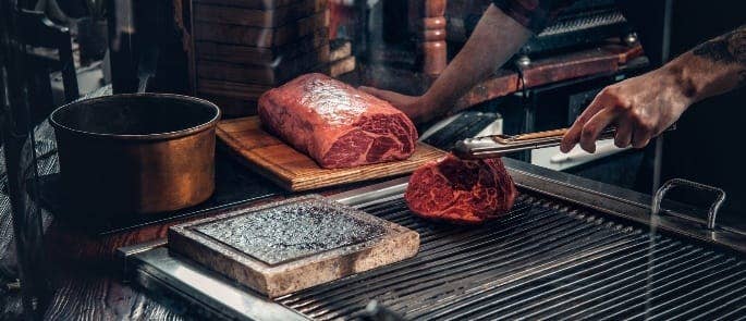 Chef searing and shaving a beef cut