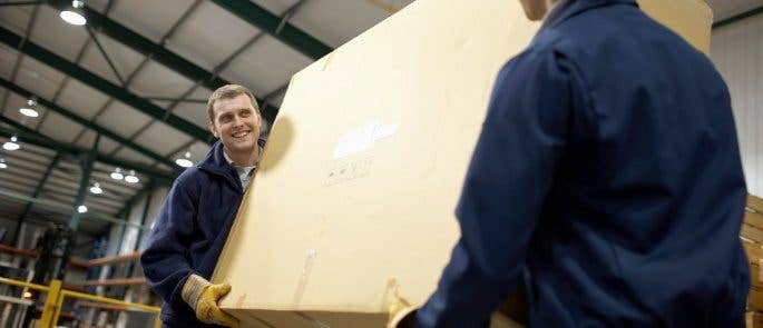 Two workers carrying a large box in a warehouse