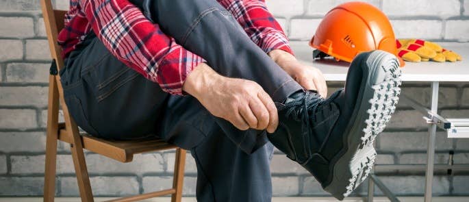 Worker putting on safety boots PPE