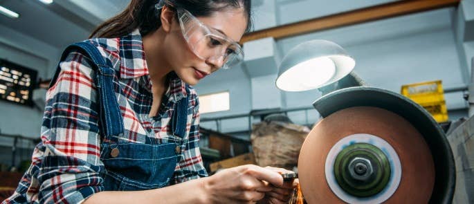 Worker using an abrasive wheel on a workpiece wearing protective glasses