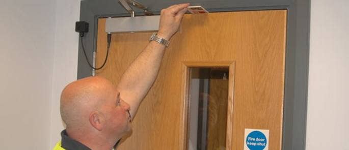 Worker using gap gauge on fire door