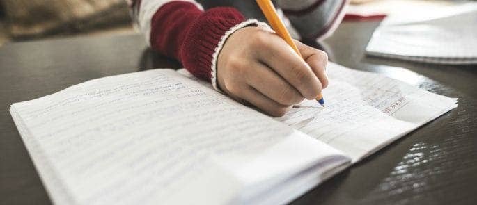 School child writing in their book.