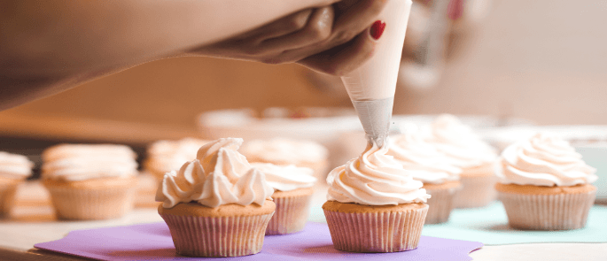 Piping buttercream onto cupcakes