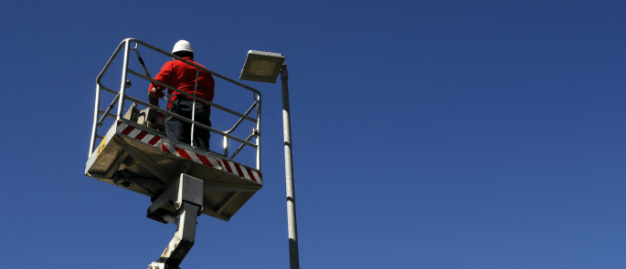 Worker working at height on a cherry picker to fix light